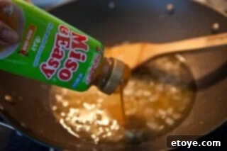Spicy Miso Steamed Mussels 5 Pouring vegetable broth into the wok