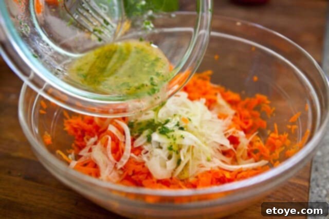 French Carrot Fennel Salad Recipe Adding the freshly prepared dressing to grated carrots and shaved fennel for a delicious French Carrot Fennel Salad