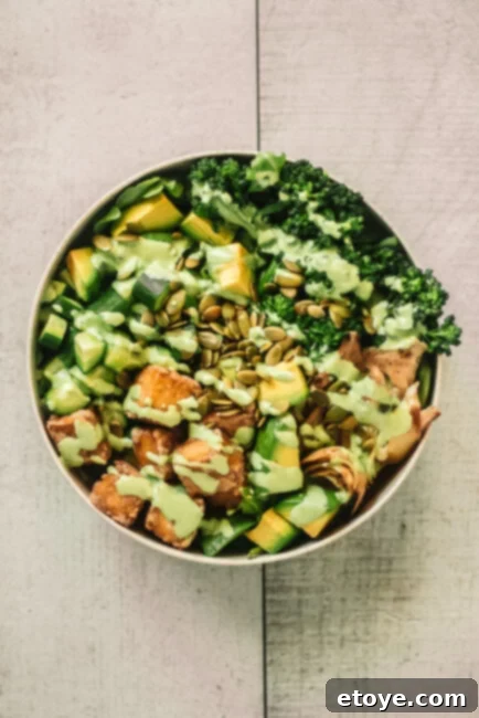 Overhead view of a beautifully arranged Green Goddess Tofu Bowl with fresh herbs and creamy dressing