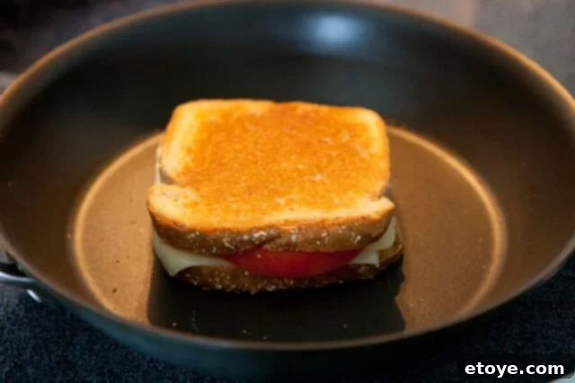 Frico-Crusted Grilled Cheese 3 Classic grilled cheese sandwich cooking to golden perfection in a skillet.