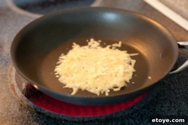 Frico-Crusted Grilled Cheese 4 Freshly grated Parmesan cheese sprinkled evenly in a hot skillet, ready to form a frico.