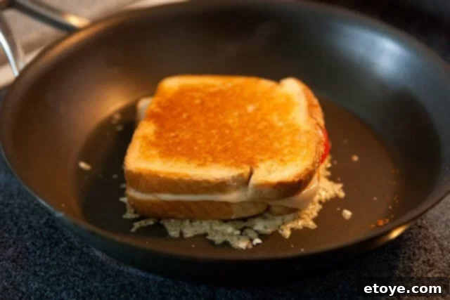 Frico-Crusted Grilled Cheese 5 A freshly made grilled cheese sandwich carefully placed on top of bubbling, melting Parmesan frico in a pan.