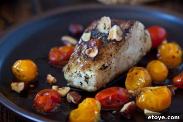 Cooked Cod and Burst Cherry Tomatoes on a Plate, Ready to Serve