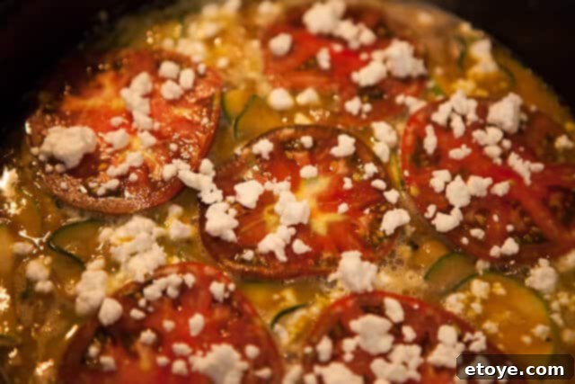 Assembling the Zucchini Frittata with eggs, tomatoes, and goat cheese before baking