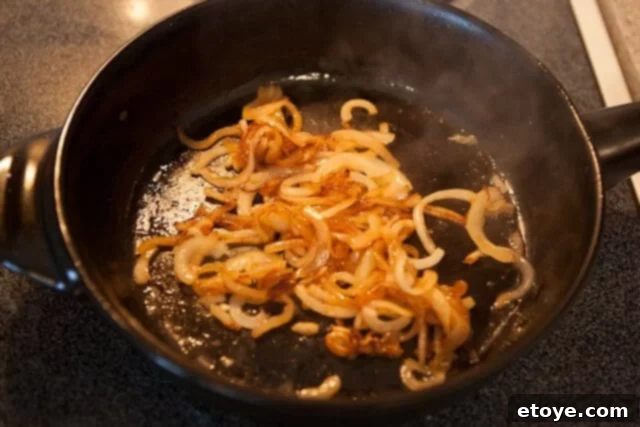 Onions slowly caramelizing in a pan with a hint of sugar