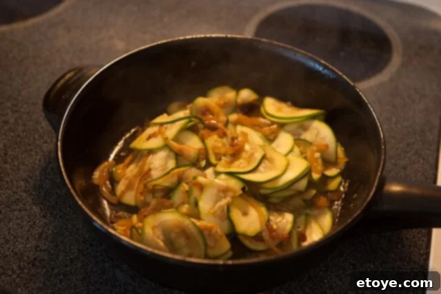 Sautéing onions and thinly sliced zucchini together in a pan