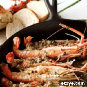A beautifully plated dish of Roasted Garlic Shrimp, garnished with fresh parsley and a slice of lemon, next to crusty bread.
