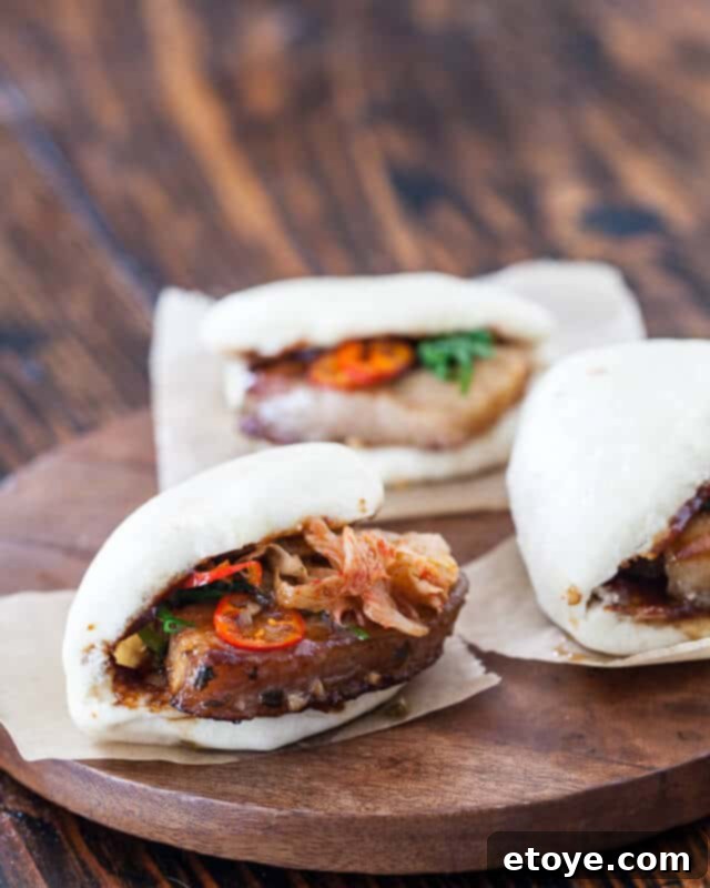 Delicious Homemade Pork Belly Buns Pork Belly Buns Recipe - Appetizing image of finished buns with pork, kimchi, and chili topping