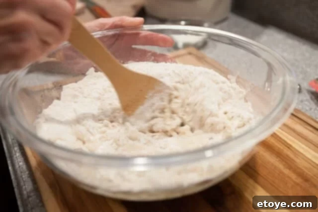 Thoroughly Combining Dough Ingredients Stirring Dough for Buns - Mixing dough in a large bowl with a wooden spoon