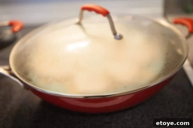 Steaming Process for Pillowy Buns Buns Steaming - Covered wok with buns steaming inside