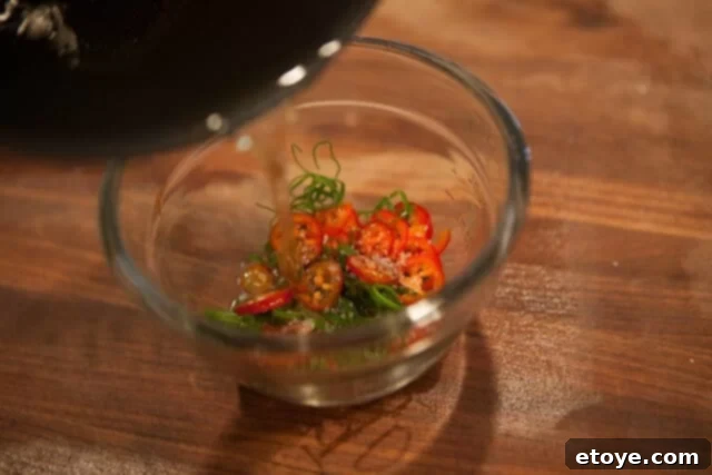 Sizzling Chili Green Onion Topping Infusion Adding Hot Oil to Chili Green Onion Mixture - Hot oil being poured over fresh aromatics