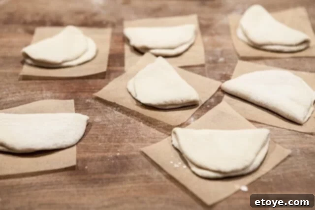 Shaping Biscuit Dough into Buns Folded Biscuits on Parchment - Shaped biscuit dough on parchment squares