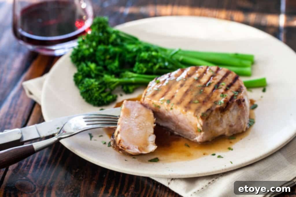 A perfectly cooked Whiskey Miso Pork Chop, sliced to reveal its juicy interior, glazed with a rich sauce