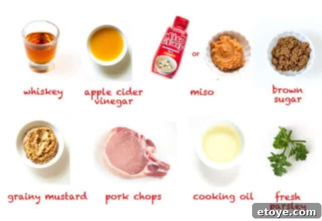 All ingredients for Whiskey Miso Pork Chops laid out on a kitchen counter, including whiskey, miso paste, apple cider vinegar, brown sugar, grainy mustard, pork chops, cooking oil, and fresh parsley