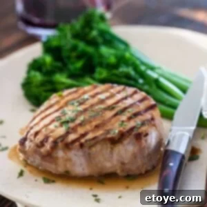 A top-down view of Whiskey Miso Pork Chops on a serving platter, glistening with sauce and garnished with fresh herbs