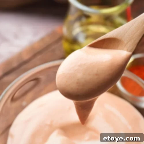 Zesty Creamy Taco Salad Dressing 5 Creamy Taco Dressing in a bowl with a wooden spoon, ready to be served over a fresh salad.