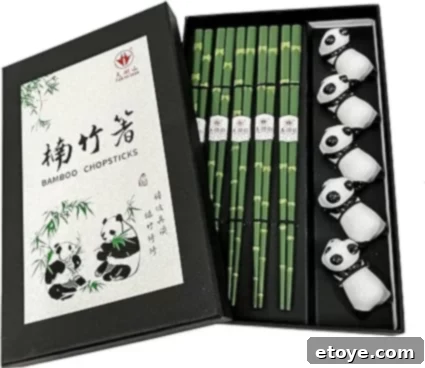 A boxed set of bamboo chopsticks with a green bamboo design, accompanied by white porcelain rests featuring cute panda faces, all presented in a sleek black box with traditional Chinese bamboo and panda illustrations on the cover.