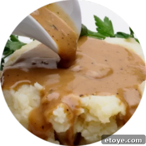 Brown gravy pouring on mashed potatoes.