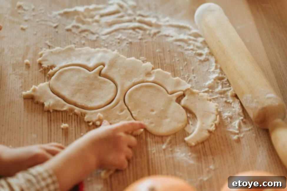 Celebrate Thanksgiving Without Breaking the Bank 2 Dough cut into a pumpkin shape with a kids hand and rolling pin, symbolizing hands-on, budget-friendly meal preparation.