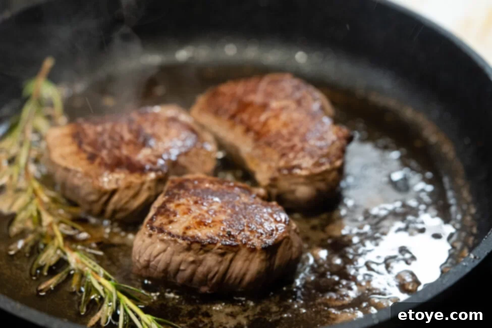 Seared steak cooking in a cast iron skillet on a stovetop