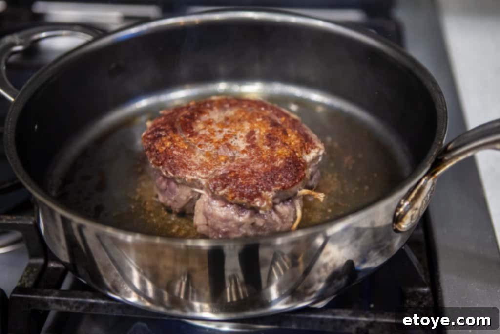 A perfectly cooked medium-rare steak, sliced and served on a plate with fresh herbs
