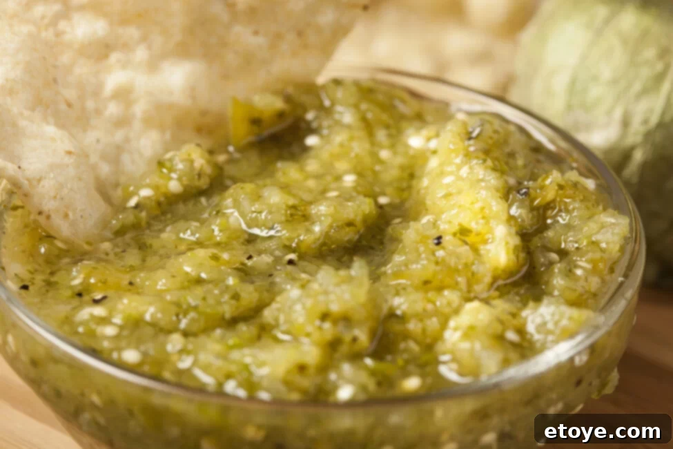 Assortment of fresh ingredients for salsa verde on a cutting board with a blender in the background