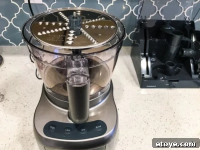 Getting Started With Your Food Processor 4 A person adding ingredients to a food processor through the feed chute.