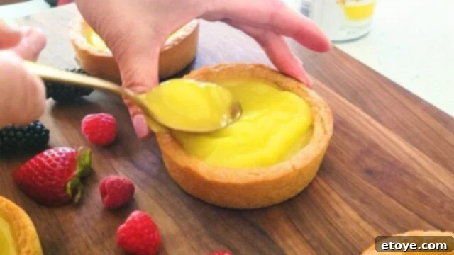 Putting lemon pie filling in a cookie tart