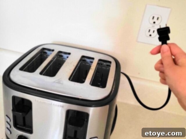 Get a Spotless Toaster Fast and Effortlessly 5 A hand unplugging a toaster from a wall outlet, emphasizing safety