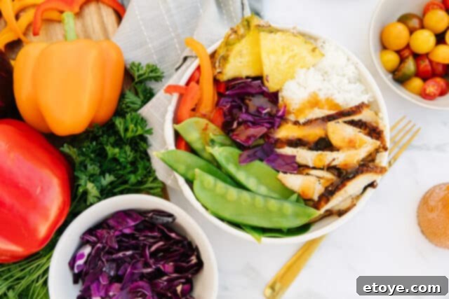 Ingredients laid out for a healthy pineapple chicken Buddha Bowl, including fresh produce and protein