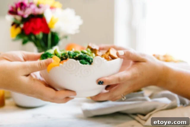 A hand gently placing a fresh Buddha Bowl onto a serving table, ready to be enjoyed