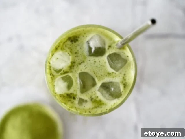 Starbucks Green Tea Matcha Latte Ingredients 5 A high-angle shot of an iced matcha latte, garnished with a straw and a slight condensation on the glass.