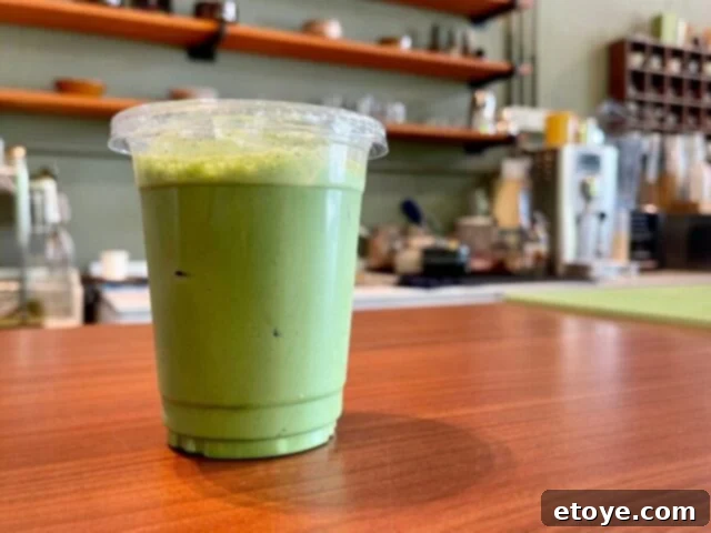 Starbucks Green Tea Matcha Latte Ingredients 6 A homemade matcha latte in a glass, placed on a kitchen counter next to a matcha whisk and a small bowl, ready to be enjoyed.