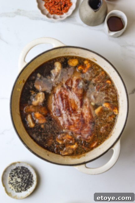 Beef chuck roast braising in umami-rich broth