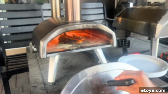 A child enthusiastically topping their mini pizza with various fresh ingredients.