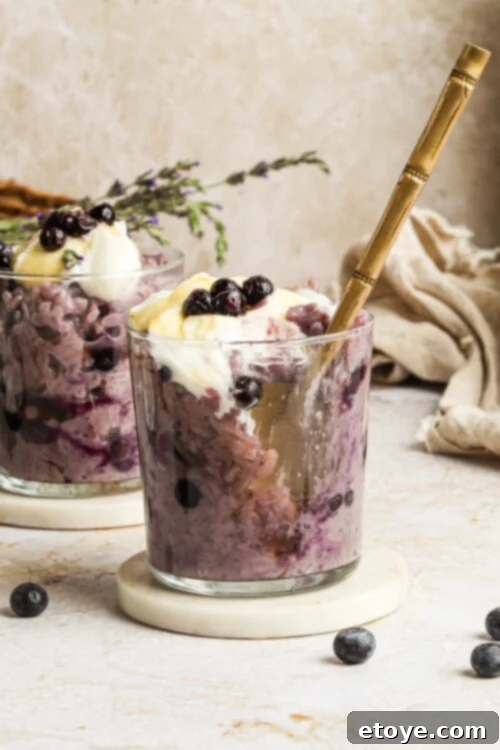 Creamy Blueberry Lavender Coconut Rice Pudding in a bowl, garnished with fresh blueberries and lavender