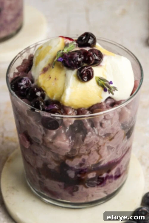 Garnished Blueberry Lavender Coconut Rice Pudding with fresh blueberries and lavender sprigs