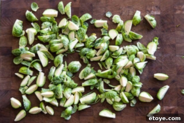 Sweet and Savory Brussels Sprouts with Lap Cheong 5 Freshly washed and quartered Brussels sprouts on a cutting board, ready for roasting.