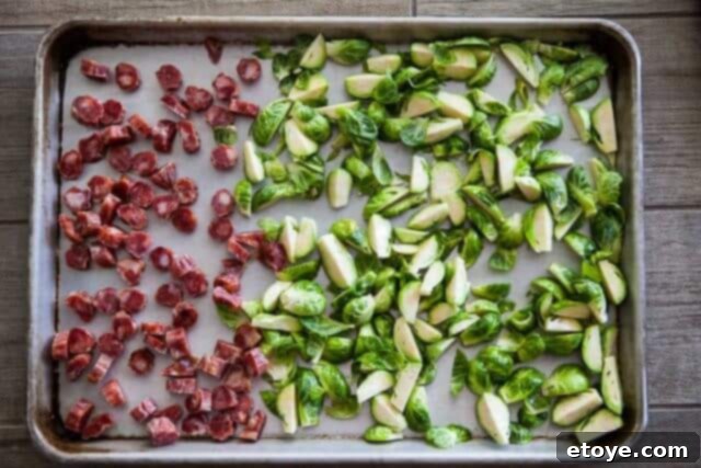 Sweet and Savory Brussels Sprouts with Lap Cheong 6 Sliced Chinese sausage and quartered Brussels sprouts separated on a baking sheet, ready for the oven.