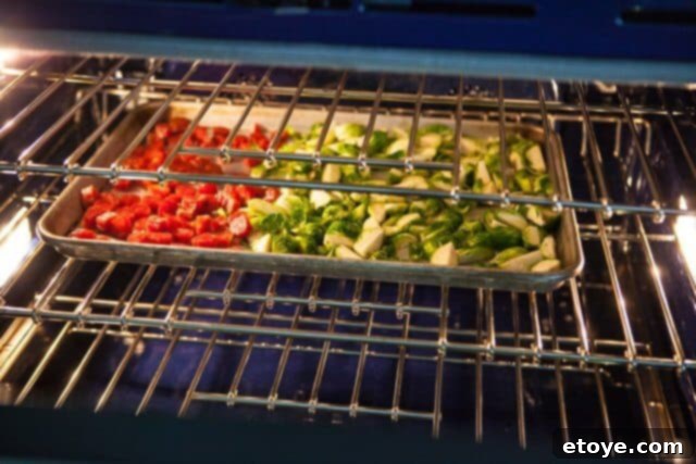 Sweet and Savory Brussels Sprouts with Lap Cheong 7 Chinese sausage sizzling on a baking sheet during the first stage of roasting, releasing its aromatic fat.