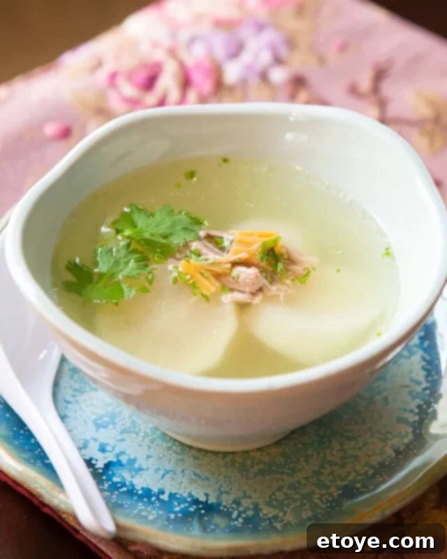 A steaming bowl of Chinese Daikon Soup, garnished with fresh cilantro, showcasing a clear, inviting broth and tender pieces of pork and daikon.
