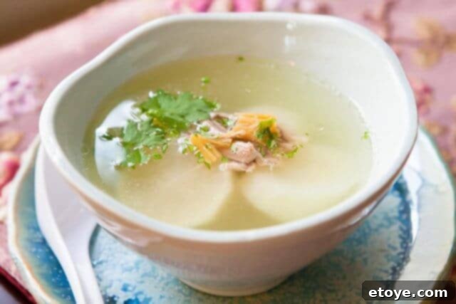 A close-up of a bowl of Chinese Daikon Soup, showing the clear broth, chunks of white daikon, and tender pork, ready to be enjoyed.