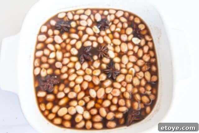 Adding raw shelled peanuts into the microwave-safe dish with seasoning.