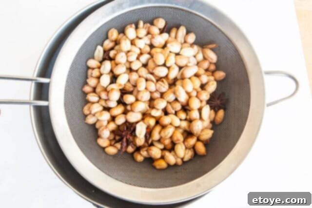 Draining liquid from microwave-cooked peanuts.