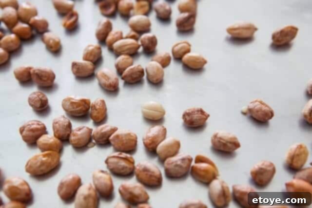 A single pale peanut among perfectly roasted ones, demonstrating varied roasting.