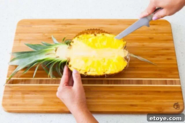 Using a sharp knife to score the pineapple flesh, carefully leaving a border near the skin