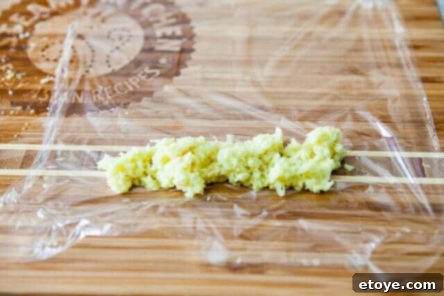 Making the Most of Leftover Ginger 9 A spoon placing finely grated ginger onto a sheet of plastic wrap for freezing