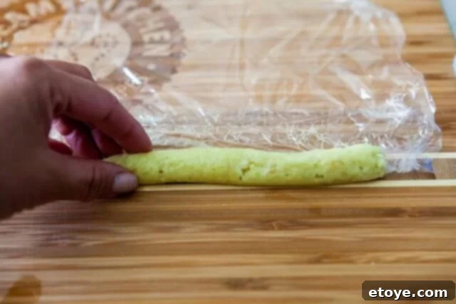 Making the Most of Leftover Ginger 10 Hands carefully rolling grated ginger into a compact cylinder using plastic wrap