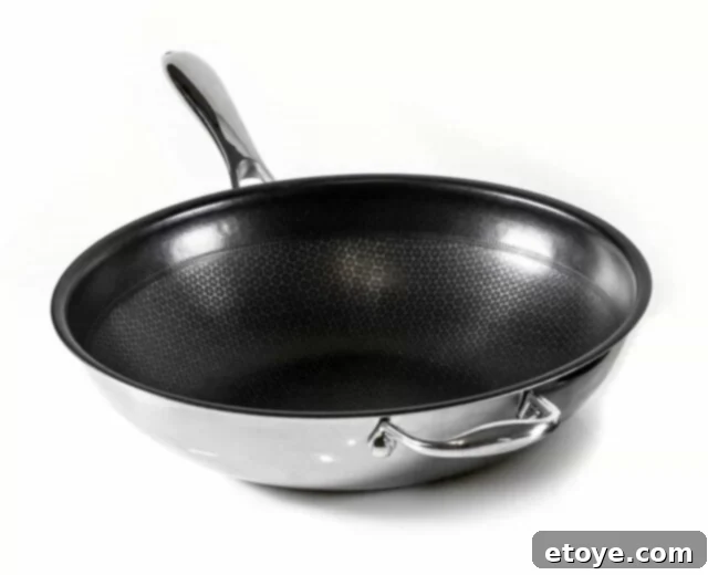 Frieling Black Cube Wok on a stovetop, showcasing its unique hybrid non-stick and stainless steel surface