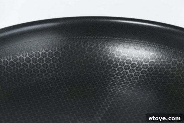 Chef using a metal spatula to stir-fry in the Frieling Black Cube Wok, demonstrating its scratch resistance